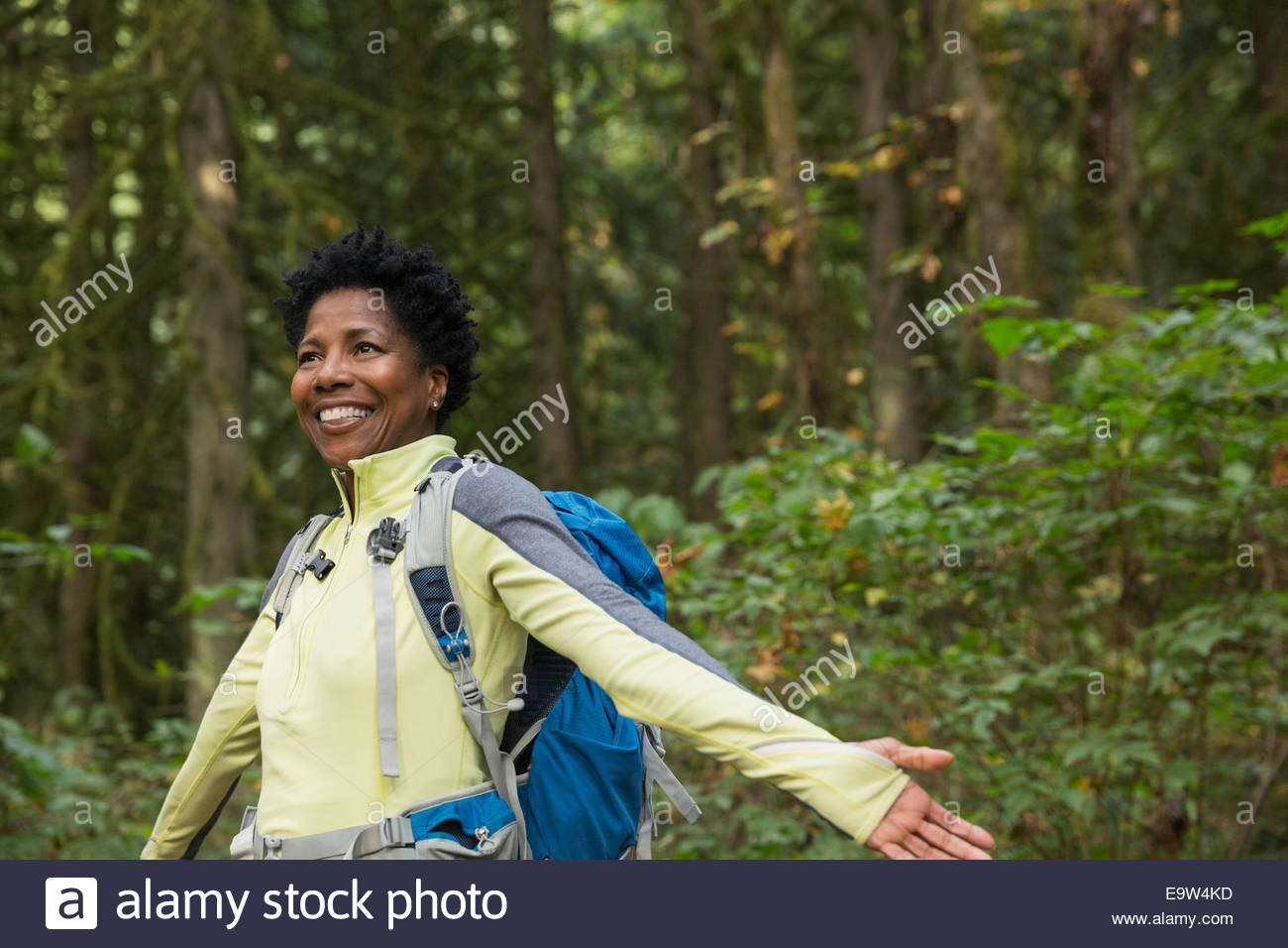 Mujer sonriente con los brazos extendidos en maderas Foto de stock