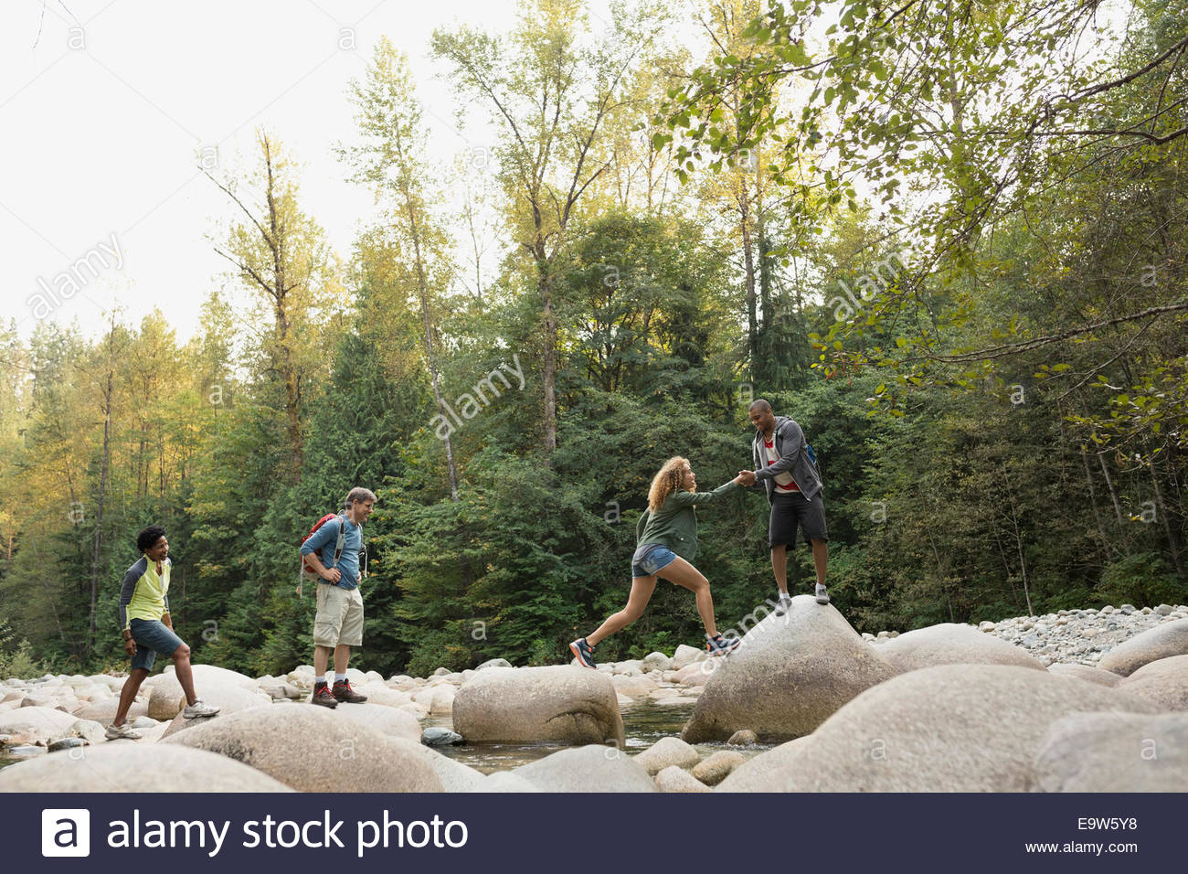 Amigos cruzando las rocas más Creek en maderas Foto de stock