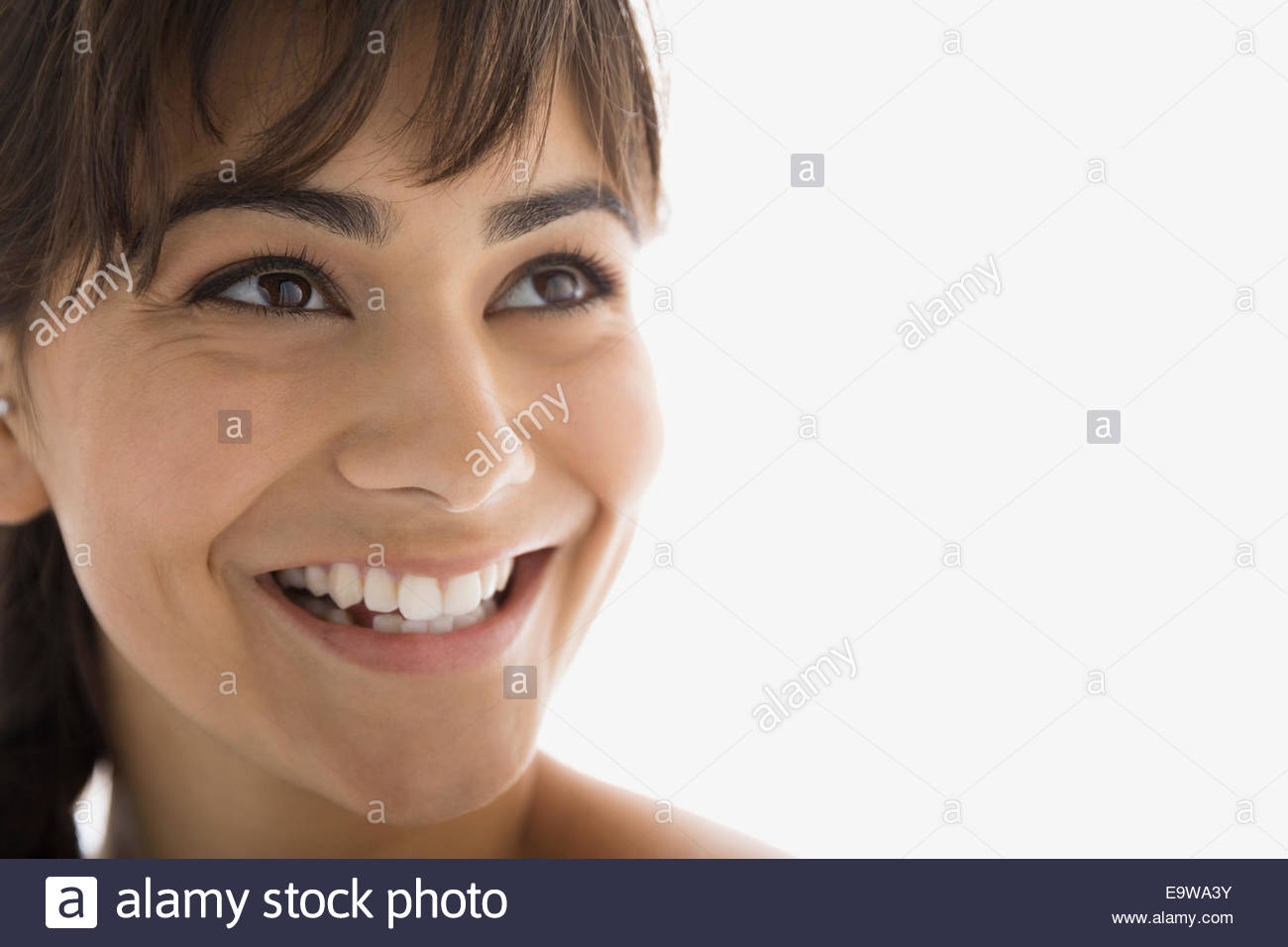 Cerca de morena sonriente mujer mirando hacia arriba Foto de stock