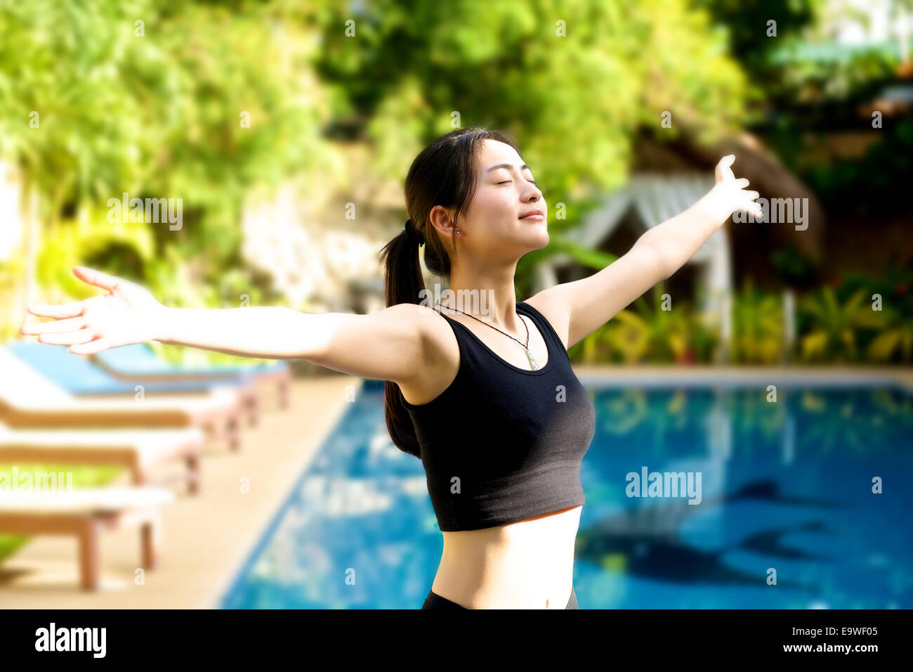 Chica asiática brazos abiertos en traje de gimnasia relajante en la piscina  Fotografía de stock - Alamy