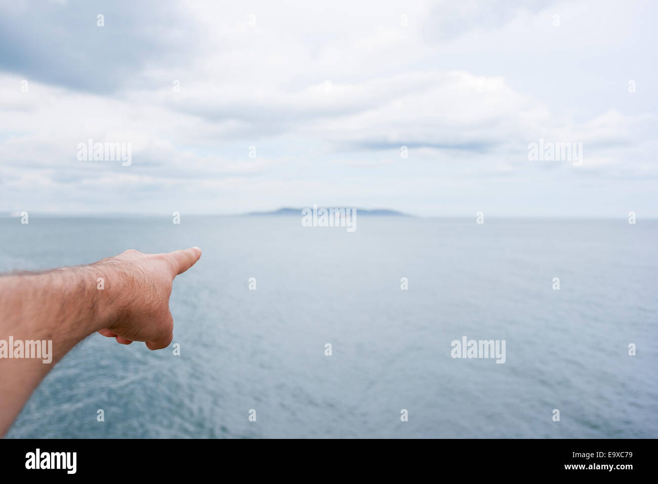 Señalar con el dedo una isla en el horizonte en el mar Foto de stock