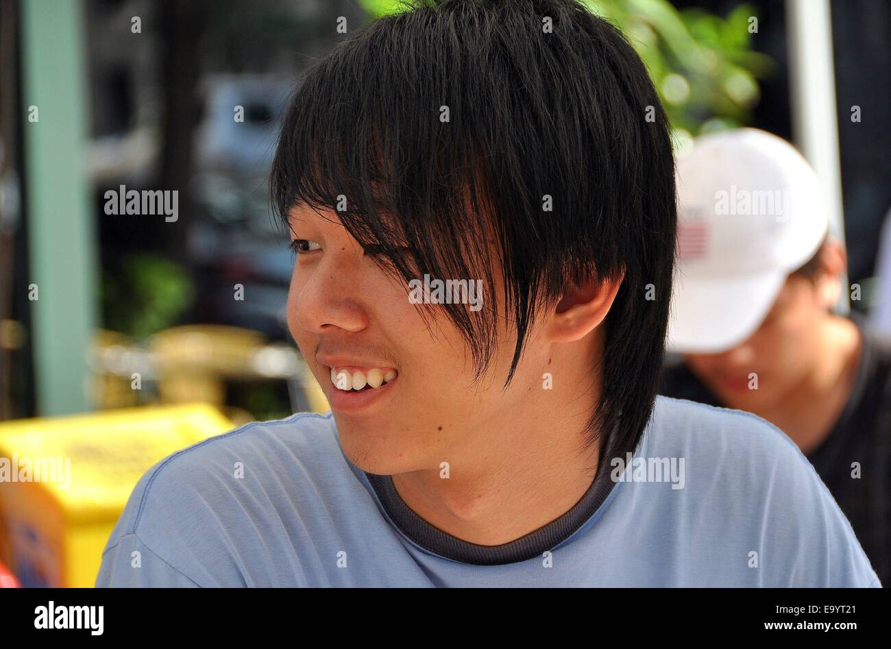 NYC: sonriente de la juventud asiática con cabello largo cubriendo su ojo izquierdo en una Avenida Amsterdam street festival Foto de stock