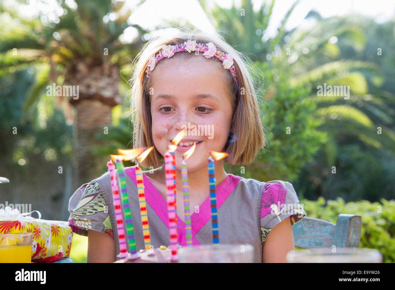 Chica de fiesta de cumpleaños mirando tarta con velas Foto de stock