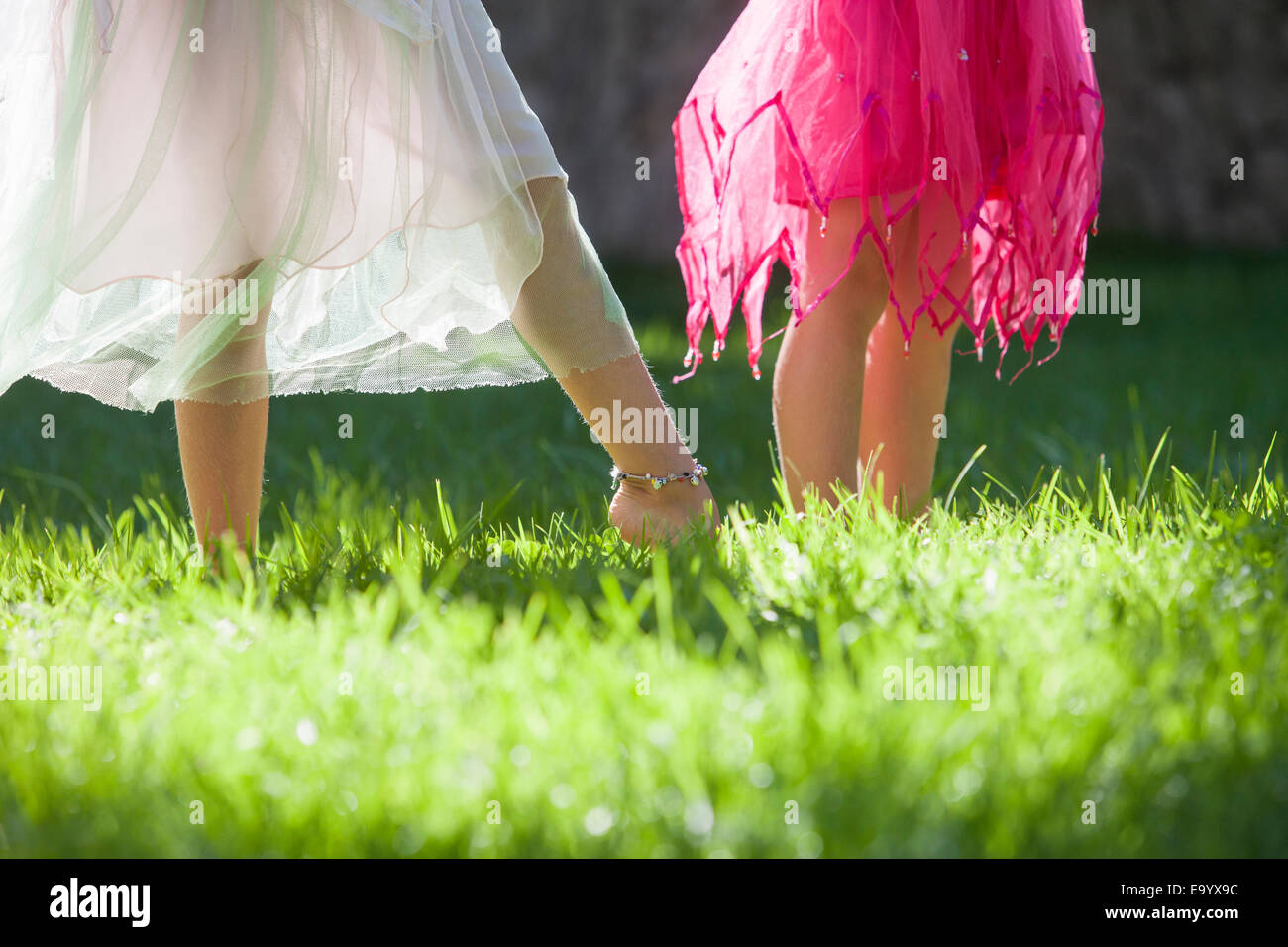 Captura recortada de la piernas de dos niñas en traje de hada en el jardín Foto de stock