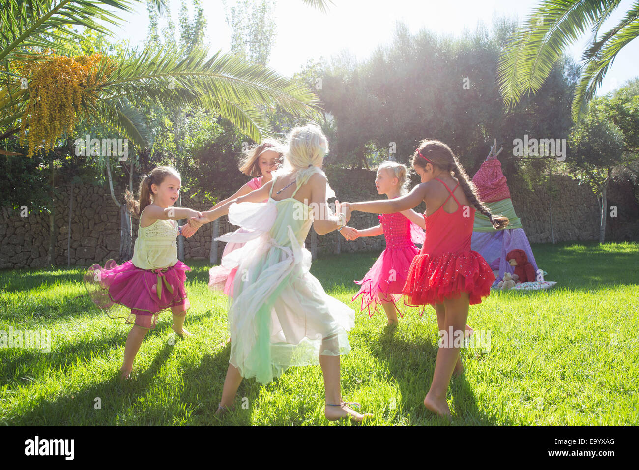 Cinco niñas enérgica en traje de hadas jugando en el jardín Foto de stock