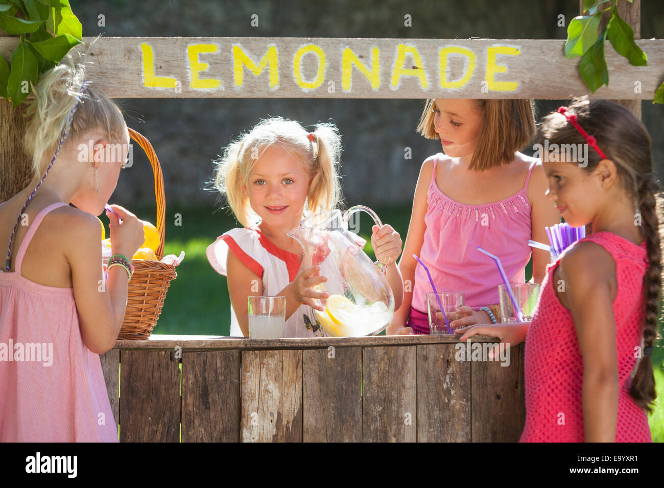 Cándido retrato de cuatro niñas en Lemonade Stand en estacionamiento Foto de stock