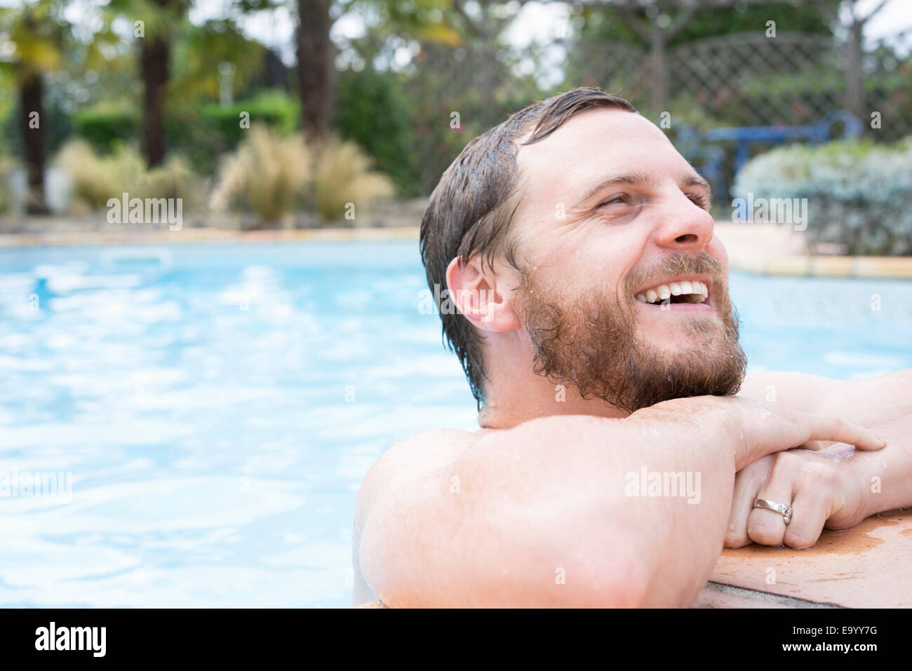 El hombre inclinado sobre el borde de la piscina Foto de stock