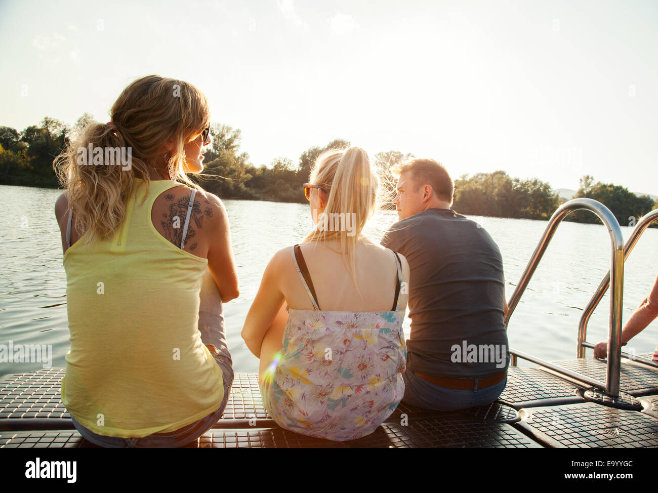 Tres jóvenes amigos adultos mirando desde el muelle de Riverside Foto de stock