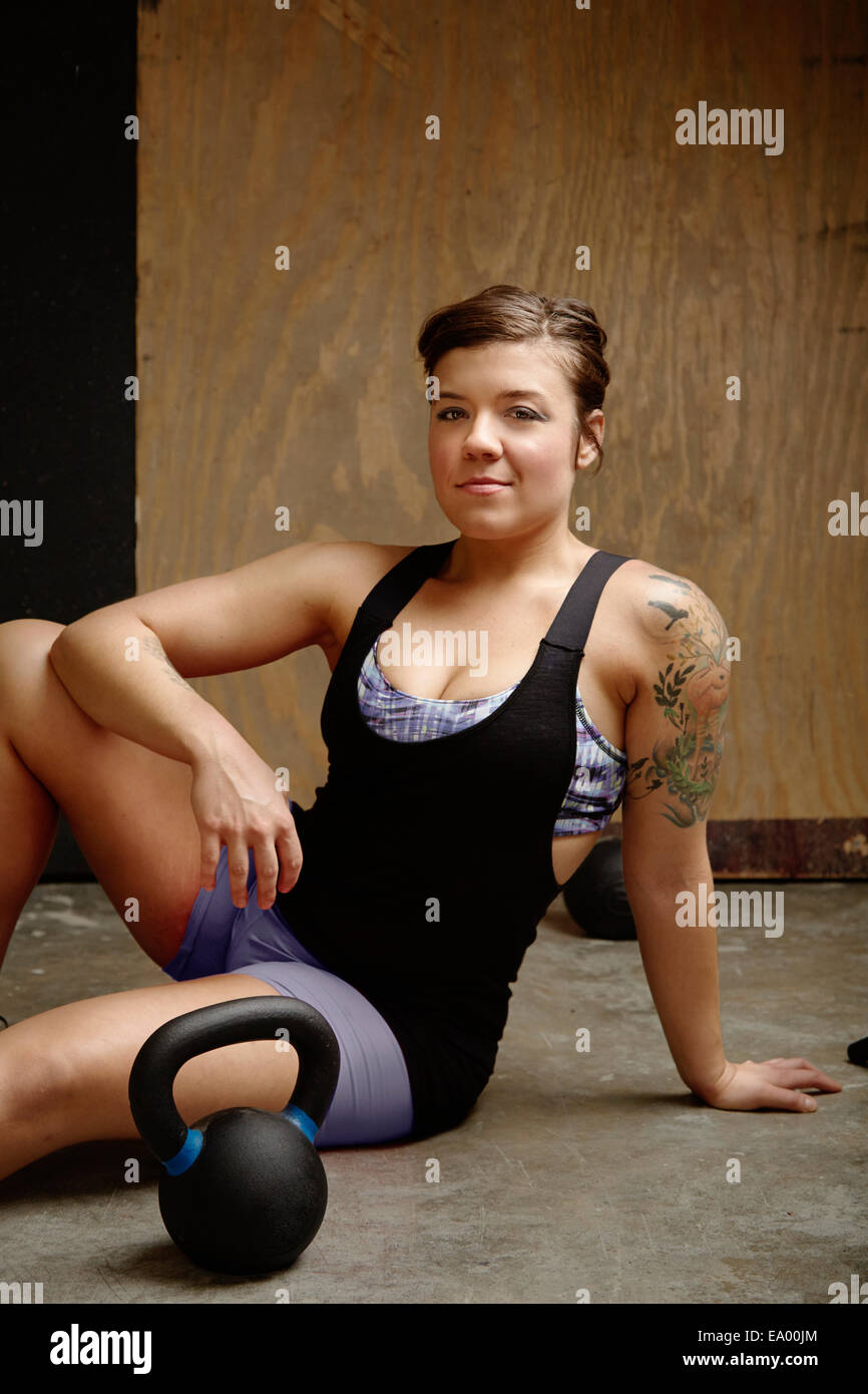 Retrato de mujer joven sentada en el suelo del gimnasio Foto de stock