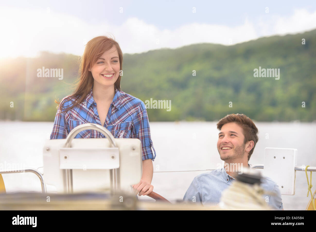 Mujer joven yate de dirección sobre el lago bajo la brillante luz del sol Foto de stock