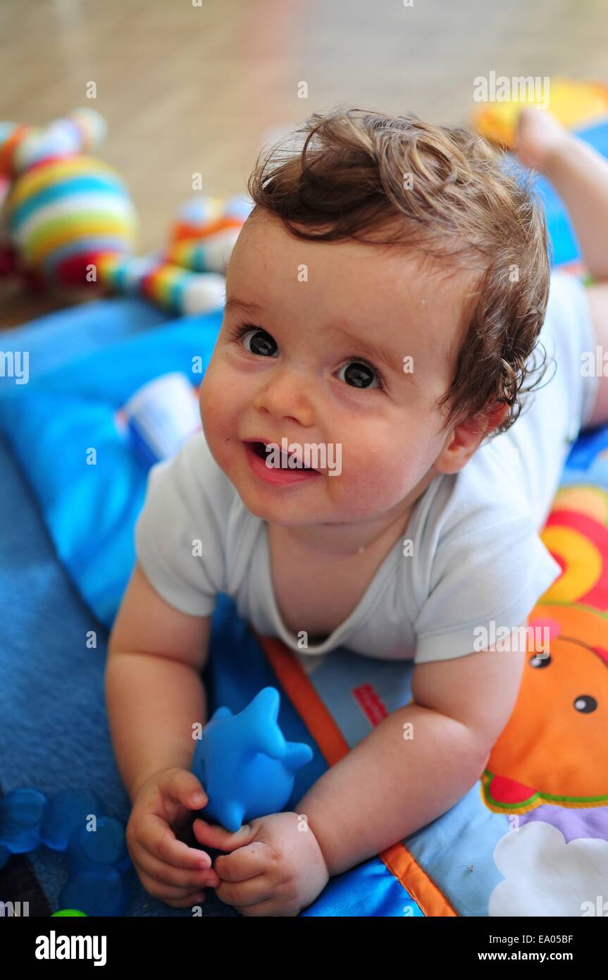 Bebé acostado sobre el estómago, jugando con el juguete Foto de stock