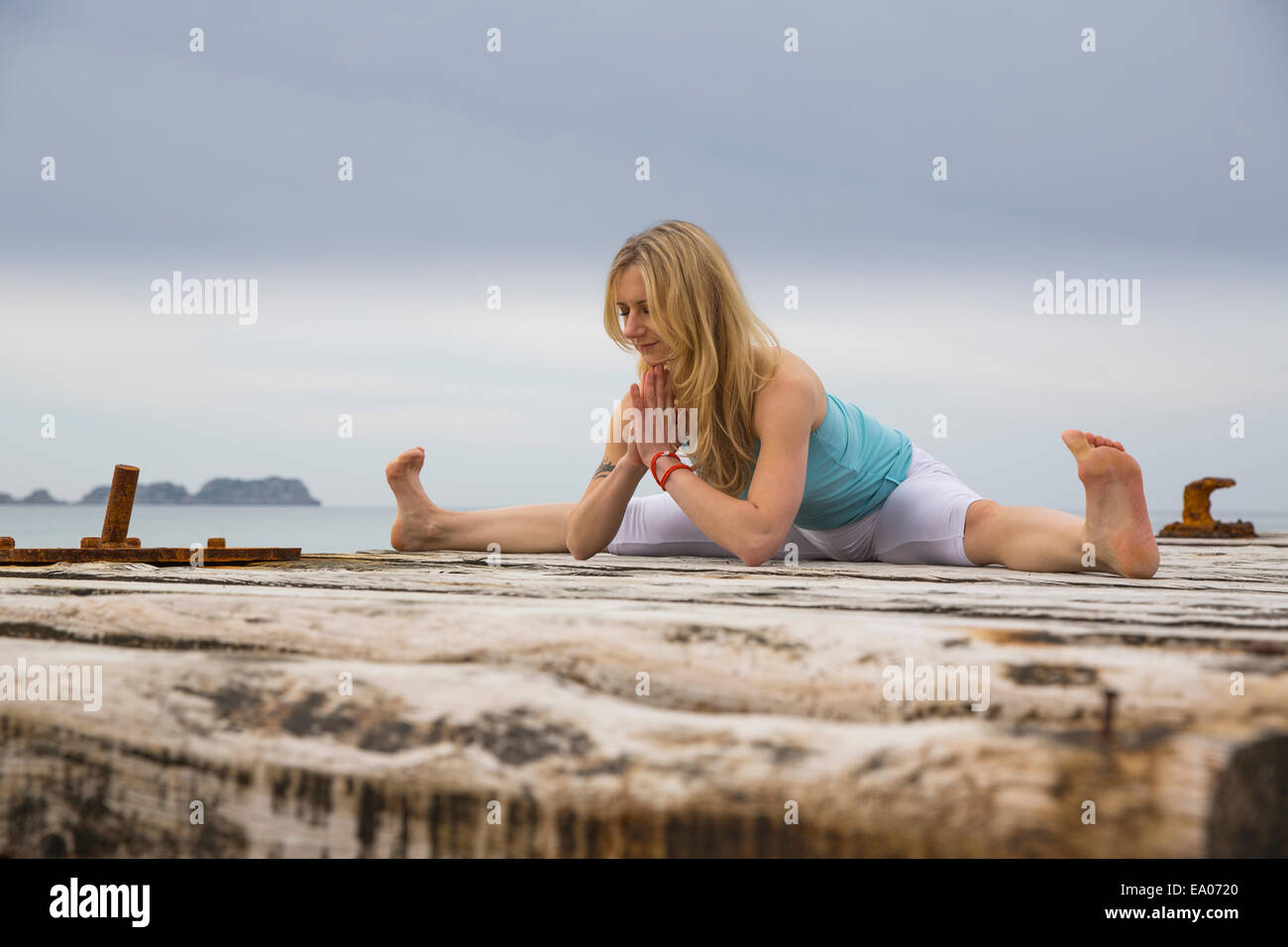 Mitad mujer adulta con manos juntas practicando yoga en Mar del muelle de madera Foto de stock