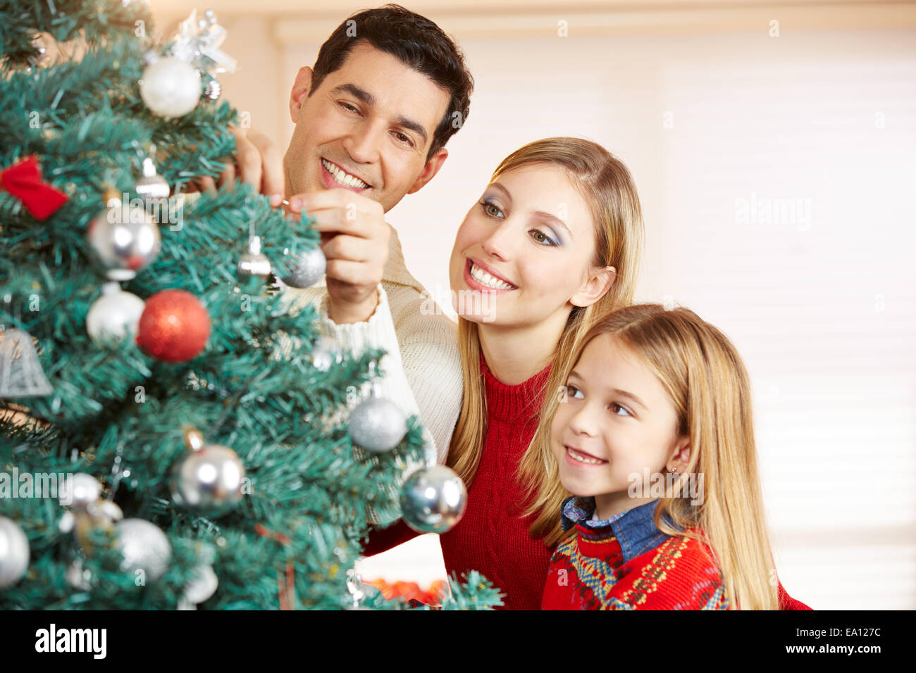 Familia Feliz decorar árbol de Navidad juntos en casa Foto de stock