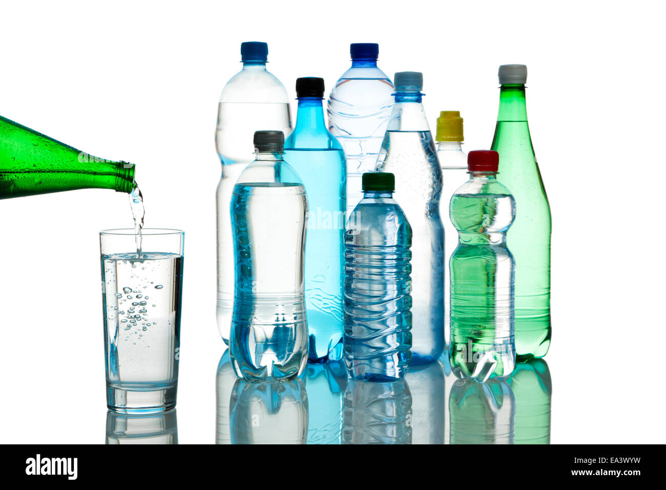 Llenar un vaso con agua mineral, Variedad de botellas de agua en segundo plano. Foto de stock