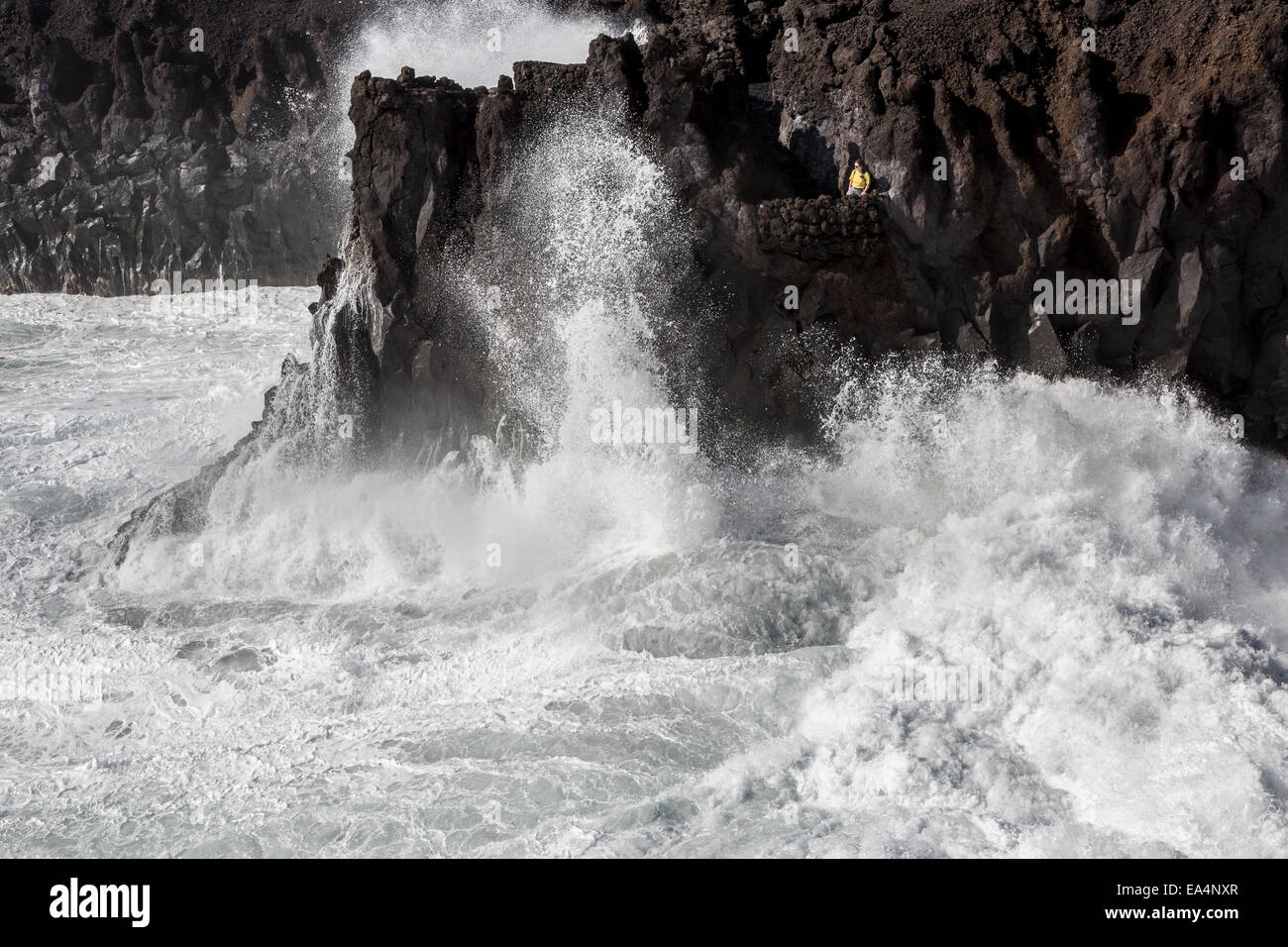 La persona que está mirando el mar embravecido Rompiendo las olas en los acantilados en Los Hervideros, Lanzarote, Islas Canarias, España Foto de stock