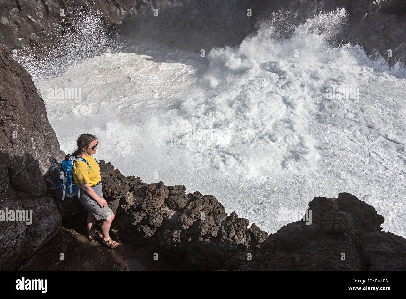 La persona que está mirando el mar embravecido Rompiendo las olas en los acantilados en Los Hervideros, Lanzarote, Islas Canarias, España Foto de stock