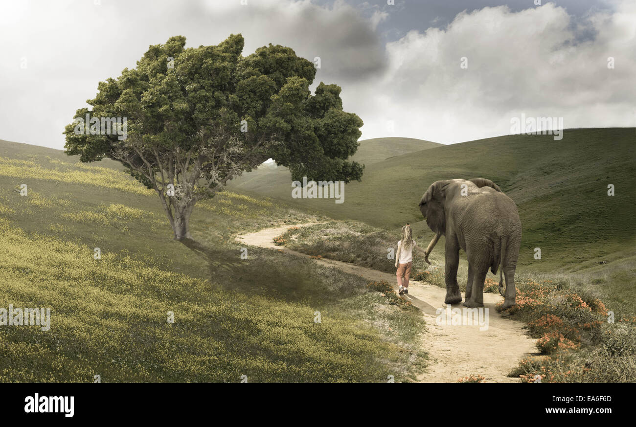 Chica caminando por un sendero con un elefante Foto de stock