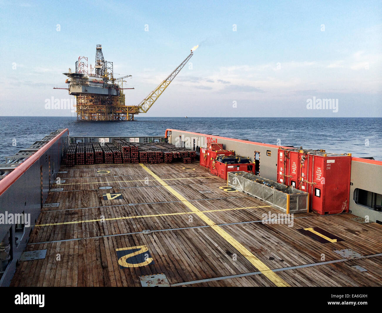 Embarcación náutica que se acerca a una plataforma petrolífera al amanecer Foto de stock