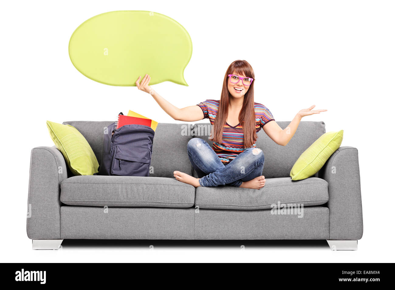 Mujer sosteniendo un discurso de burbuja sentado en un sofá aislado sobre fondo blanco. Foto de stock