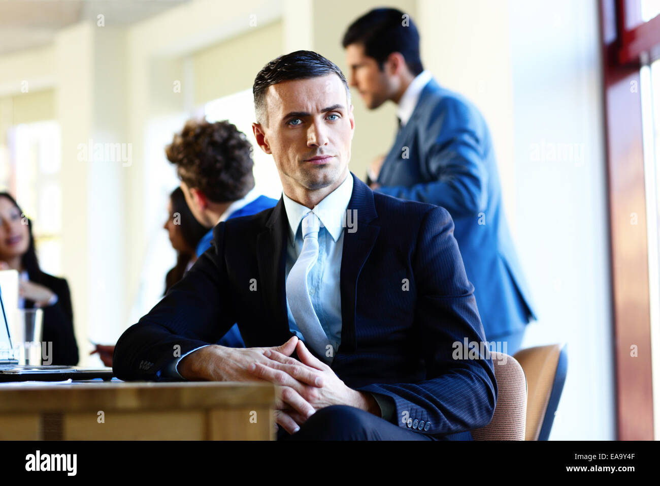 Seguros de empresario sentado a la mesa con los colegas de fondo Foto de stock