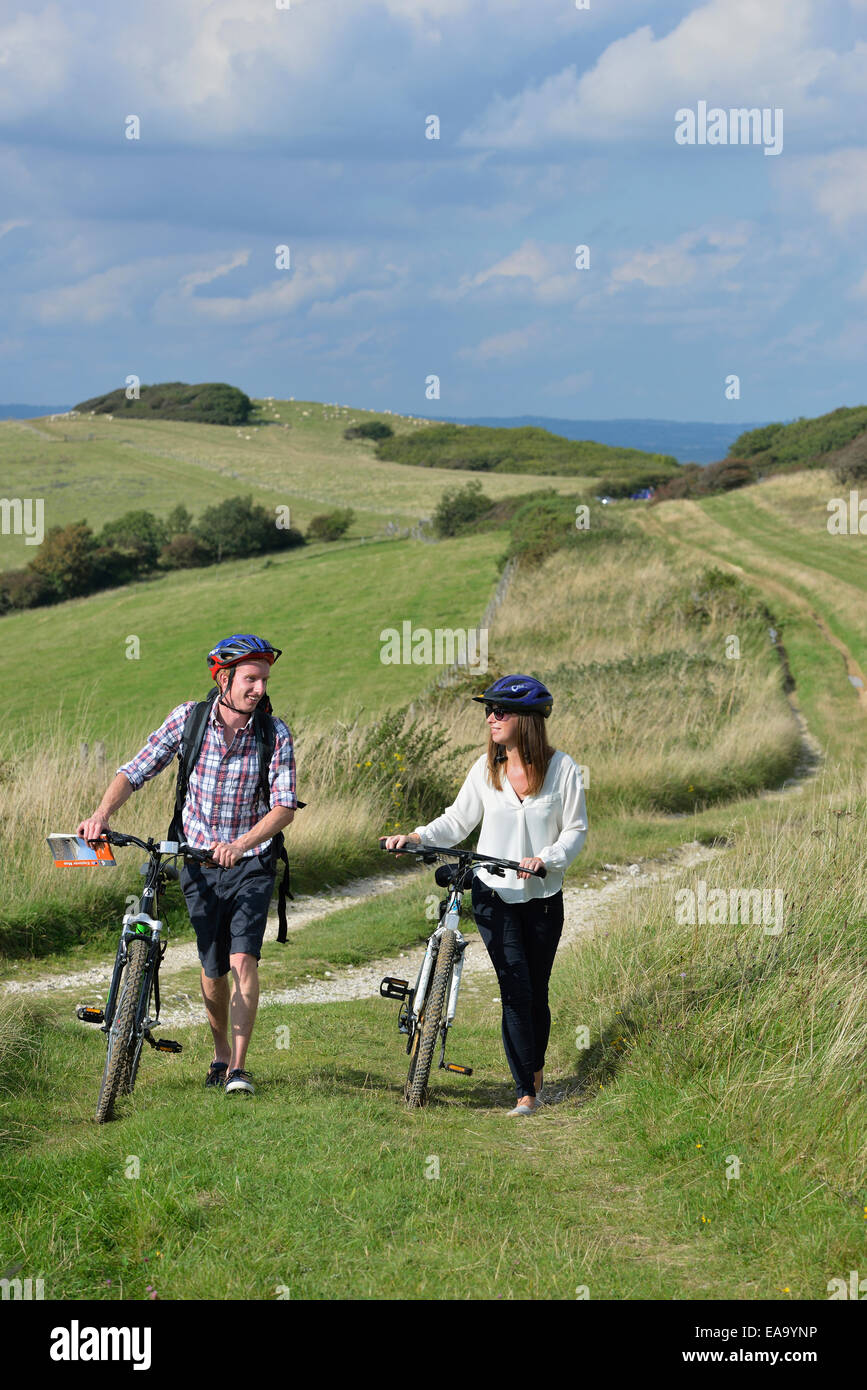 Una pareja de jóvenes adultos en bicicleta a lo largo de los South Downs Way en toneles Brow, Willingdon, cerca de Eastbourne, East Sussex. UK Foto de stock