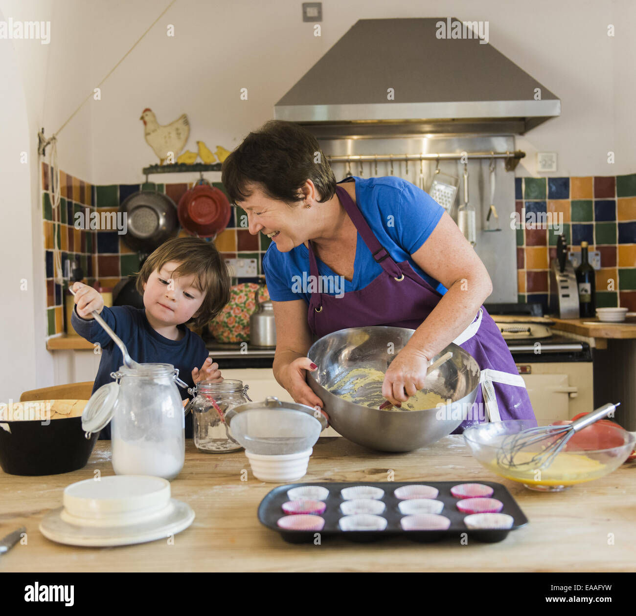 Una mujer y un niño, cocinar en una mesa de cocina, haciendo tartas de hadas. Foto de stock