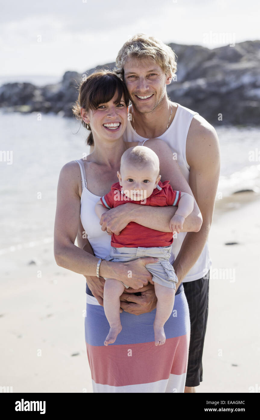 Un día en familia en la playa. Dos personas y un bebé. Foto de stock