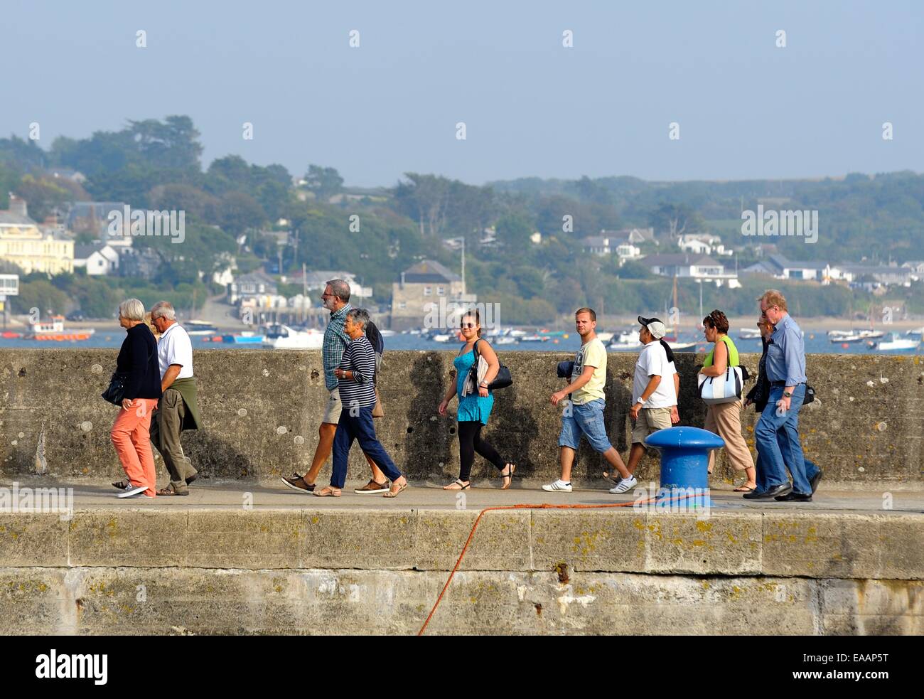 La gente caminando a lo largo de la pared del puerto después de desembarcar desde un barco. Padstow, Cornualles Inglaterra Foto de stock