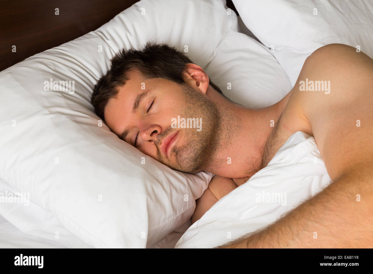 Un hombre durmiendo en la cama en la mañana Foto de stock