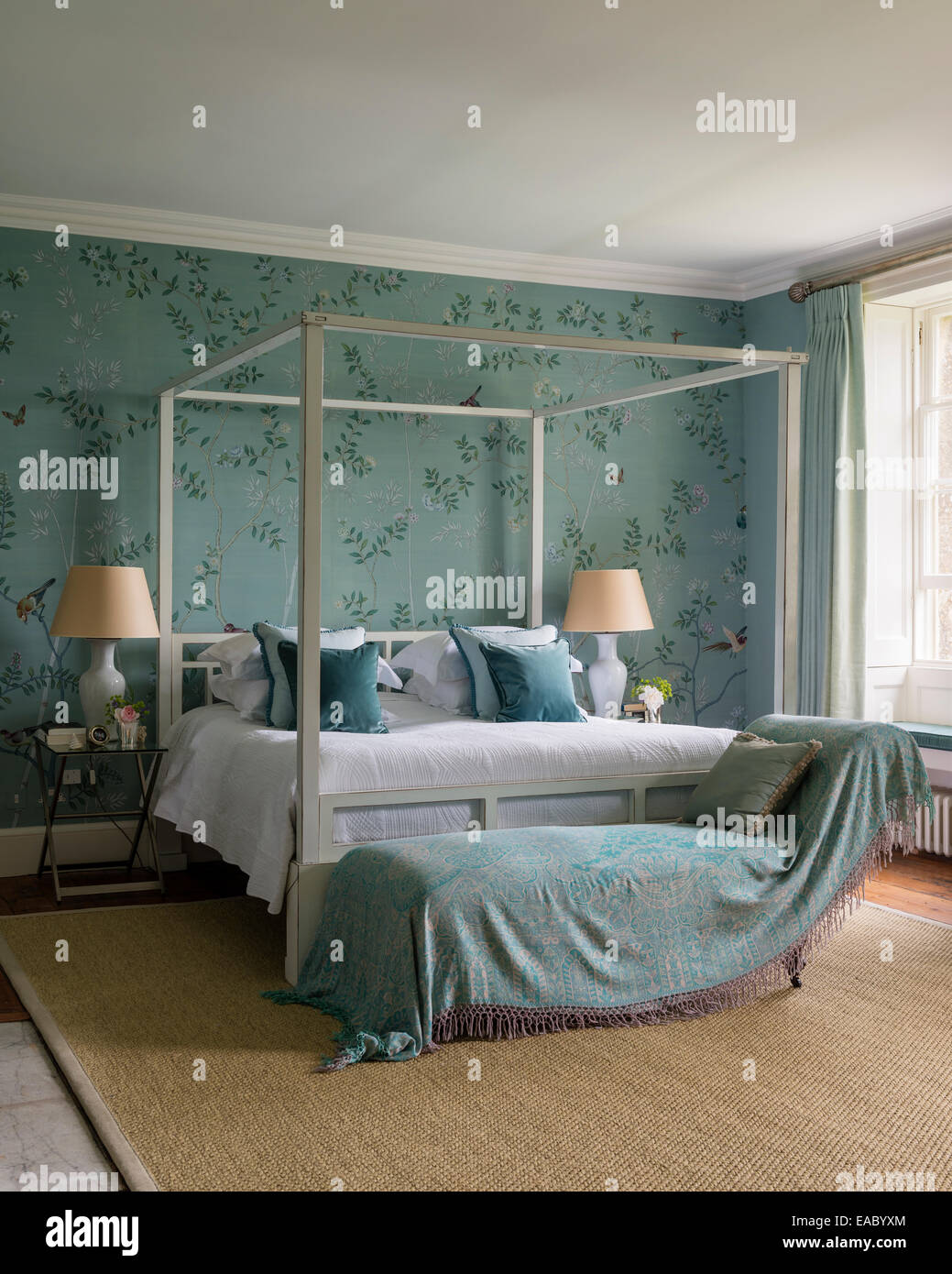 De Gournay Chinoiserie papel de seda en un elegante dormitorio con cama con dosel de ocre y alfombra de sisal Foto de stock