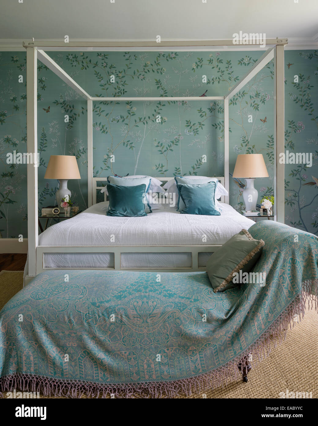 De Gournay Chinoiserie papel de seda en un elegante dormitorio con cama con dosel de ocre y alfombra de sisal Foto de stock