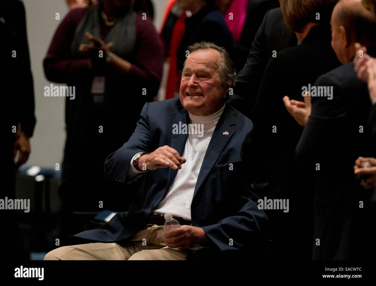 College Station, Texas, EE.UU. 11 de noviembre de 2014. El ex presidente estadounidense George H. W. Bush olas como su hijo, el ex Presidente George W. Bush habla sobre su nuevo libro, '41_un retrato de mi padre" durante un evento del libro en la biblioteca de Bush en Texas A&M University. Bush, de 90 años, fue el 41º Presidente de los Estados Unidos. Crédito: Bob Daemmrich/Alamy Live News Foto de stock
