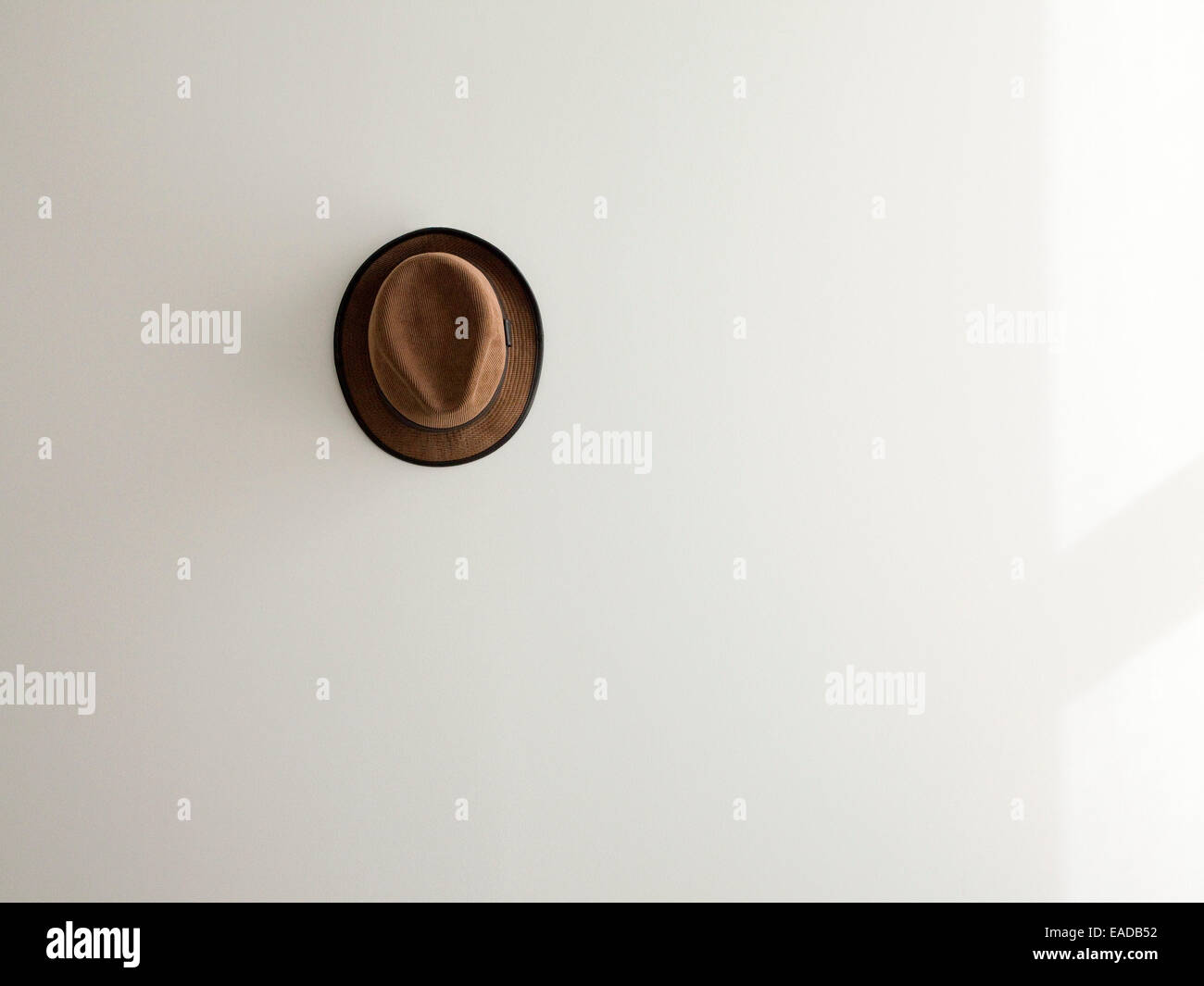Lone corduroy marrón sombrero sobre pared blanca. Foto de stock
