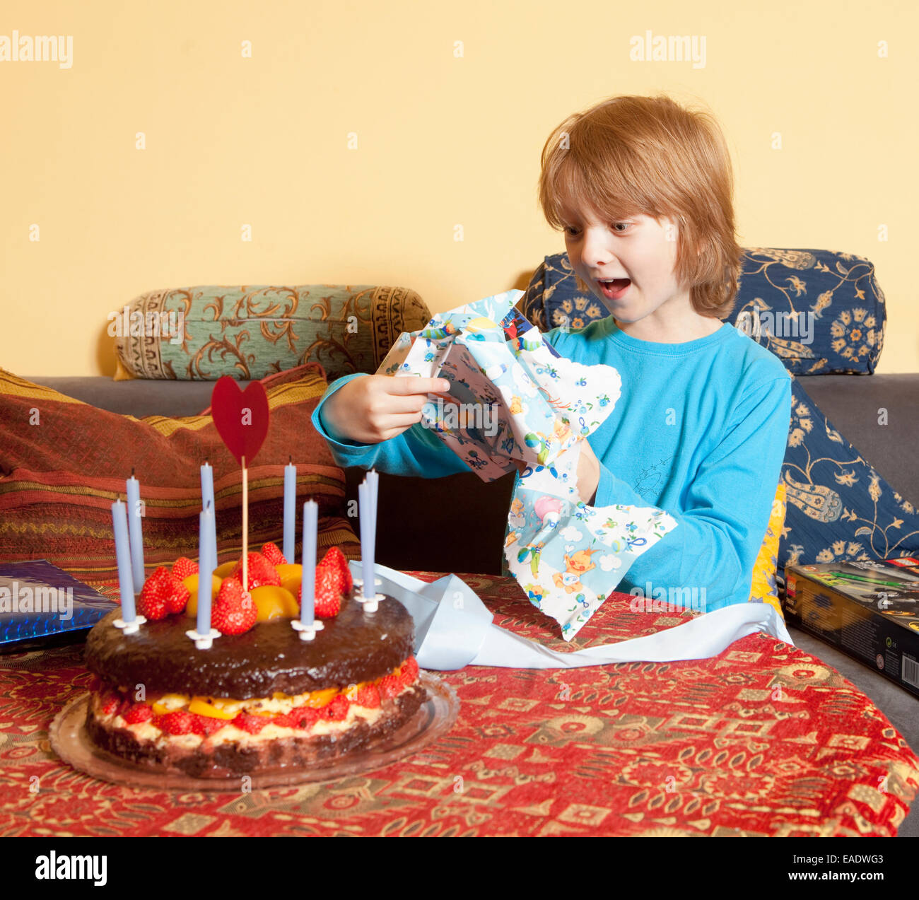 Chico con el pelo rubio abriendo sus regalos de cumpleaños Foto de stock