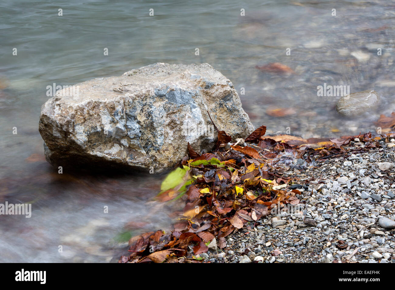 En un lago de piedra gris con coloridas hojas en otoño Foto de stock