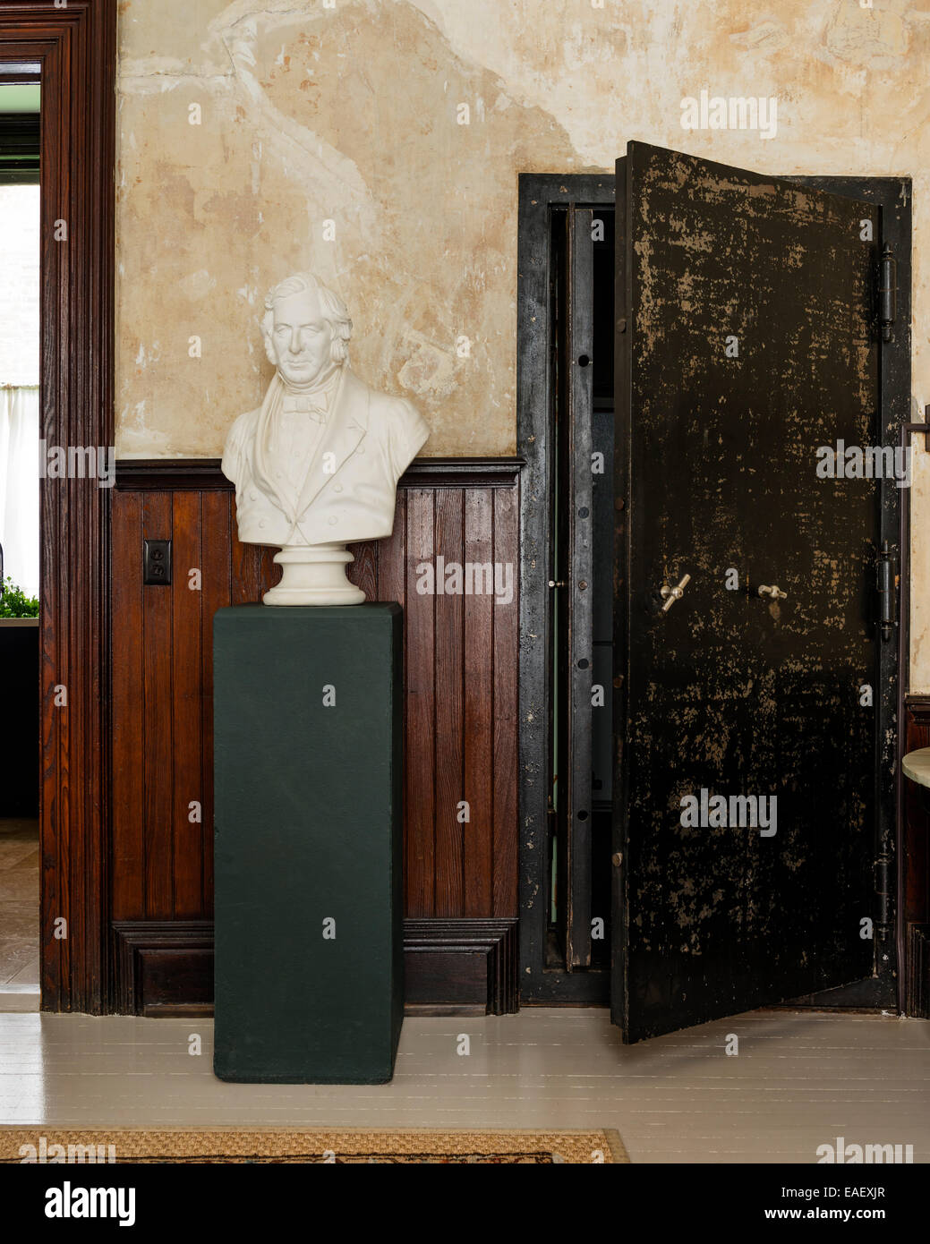 Busto de yeso sobre plinto verde en la habitación con revestimiento de madera y grandes walk-in safe Foto de stock