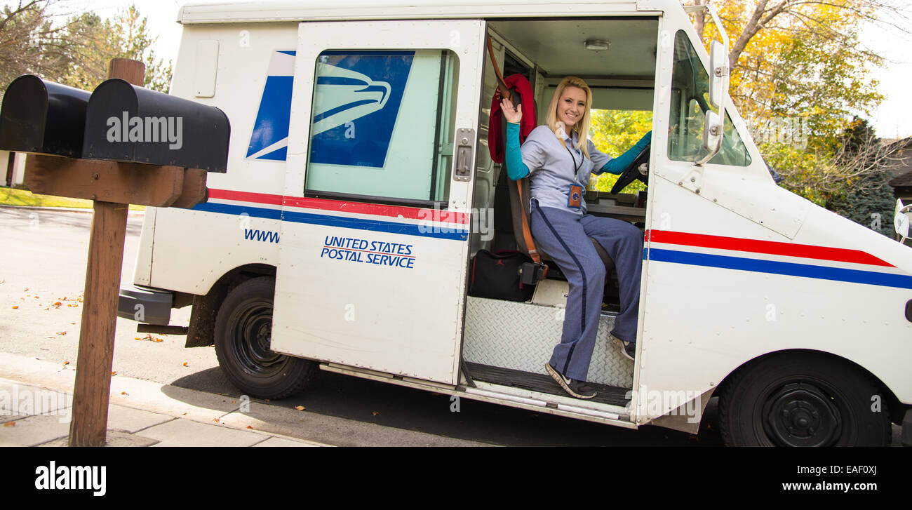 Hembra portadora del Servicio Postal de los Estados Unidos entrega correo en barrio residencial. Boise, Idaho, EE.UU. Foto de stock