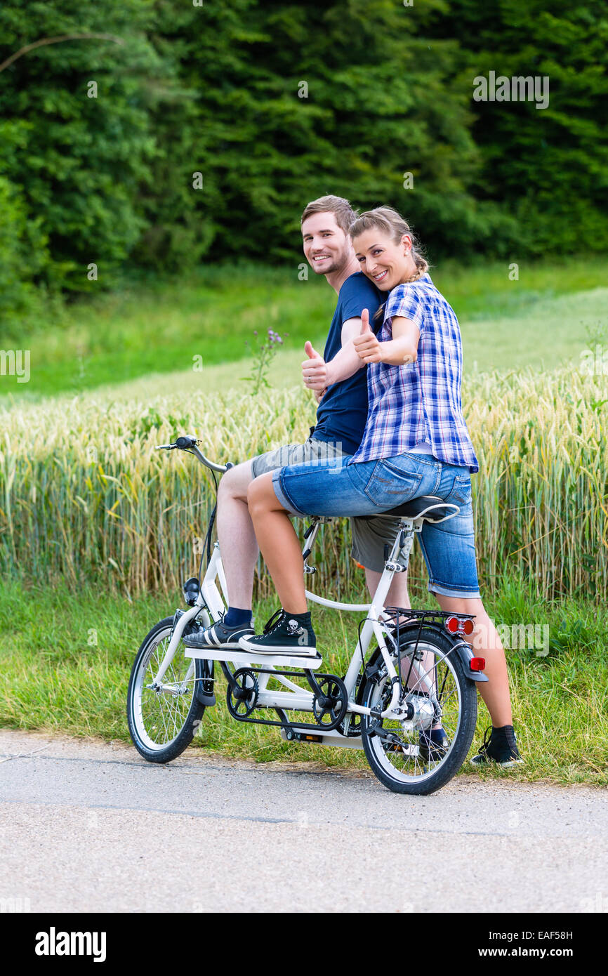 https://c8.alamy.com/compes/eaf58h/el-hombre-y-la-mujer-una-pareja-montando-bicicleta-tandem-juntos-en-carril-del-pais-eaf58h.jpg