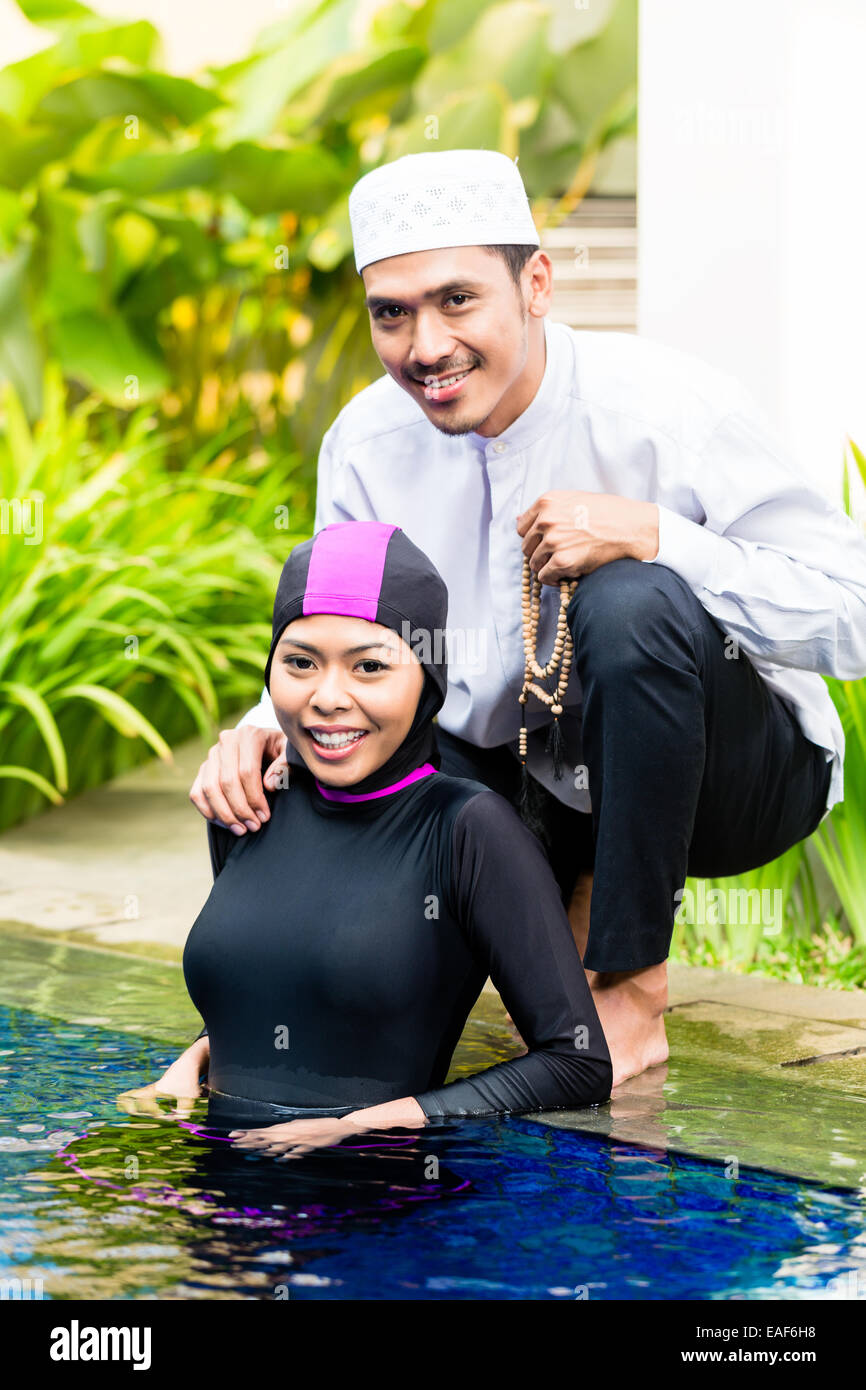 Mujer o niña musulmana en piscina en un jardín tropical vistiendo trajes de  baño halal Burkini saludo su marido Fotografía de stock - Alamy