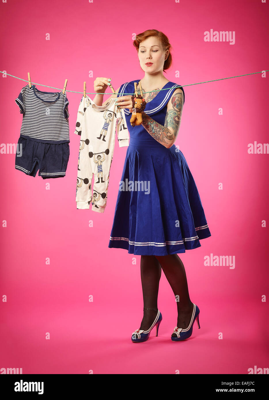 La mujer expectante colgar ropa de bebé para tendedero Foto de stock