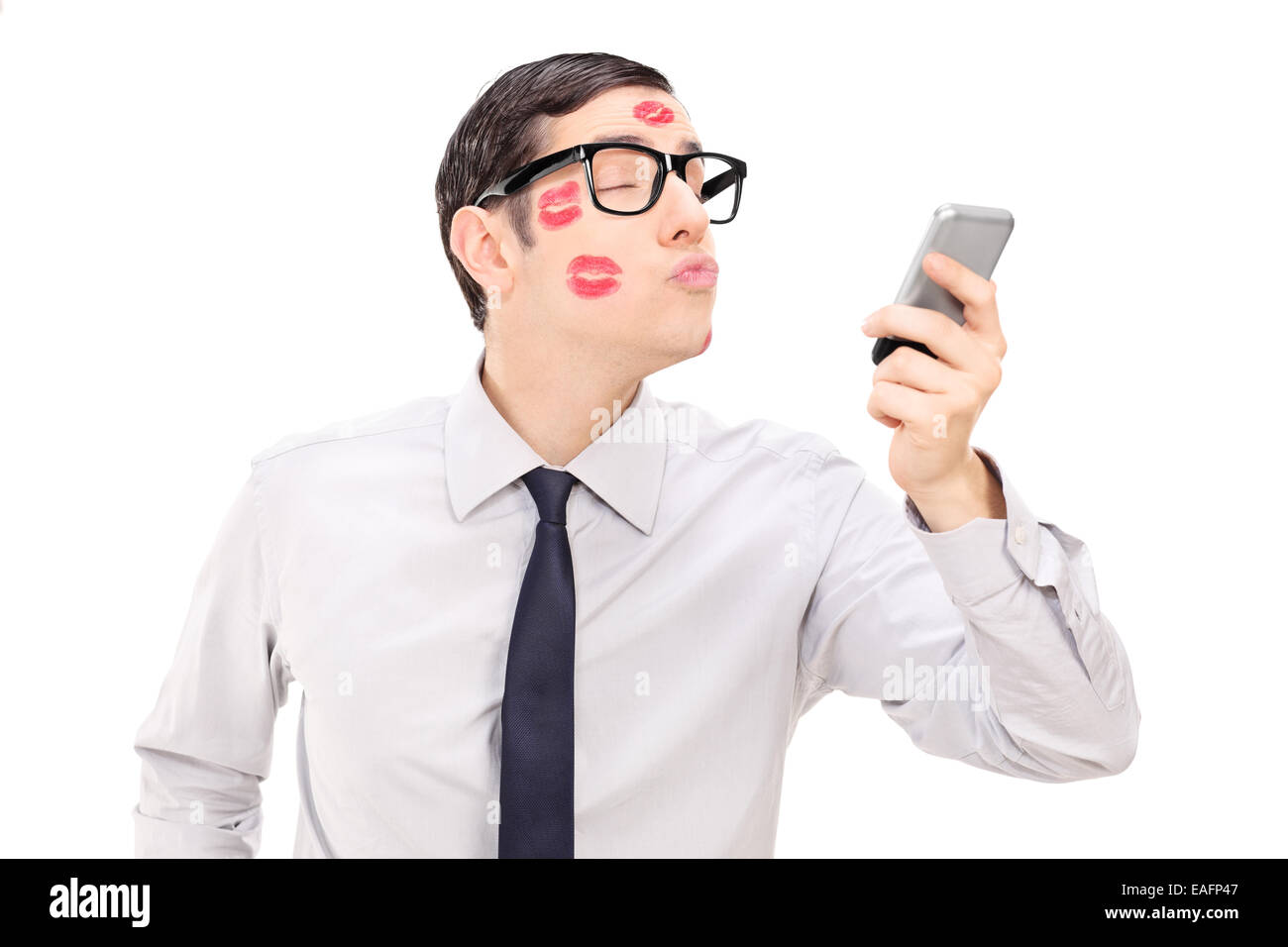 Hombre enviando un beso a través de un teléfono celular aislado sobre fondo blanco. Foto de stock