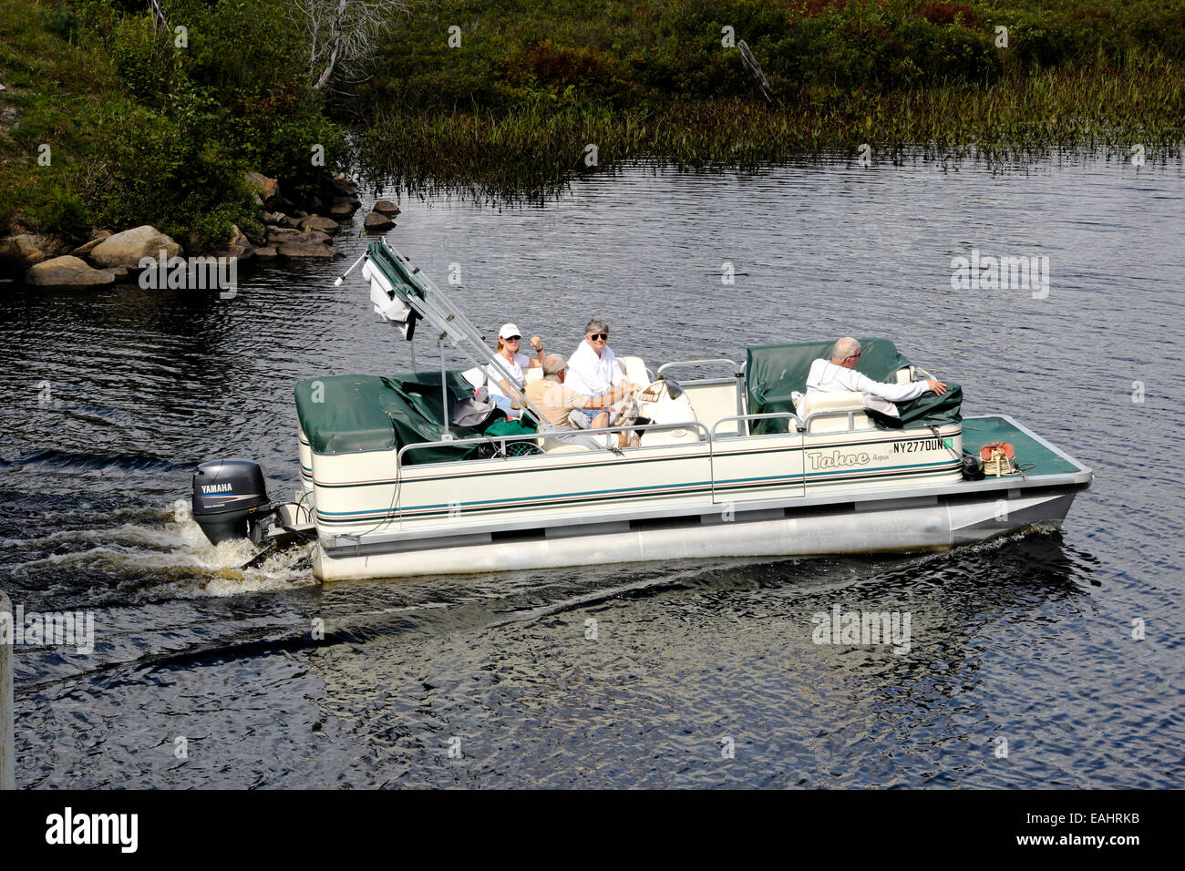 Deck Pontoon Boat con la familia automovilística navegar cerca de la orilla. El Parque Estatal de Adirondack Adirondack Mountains. Foto de stock