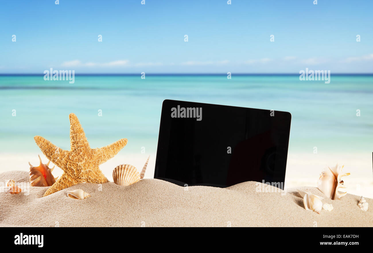 Concepto de verano con playa, tabletas y accesorios, desenfoque de fondo de mar Foto de stock