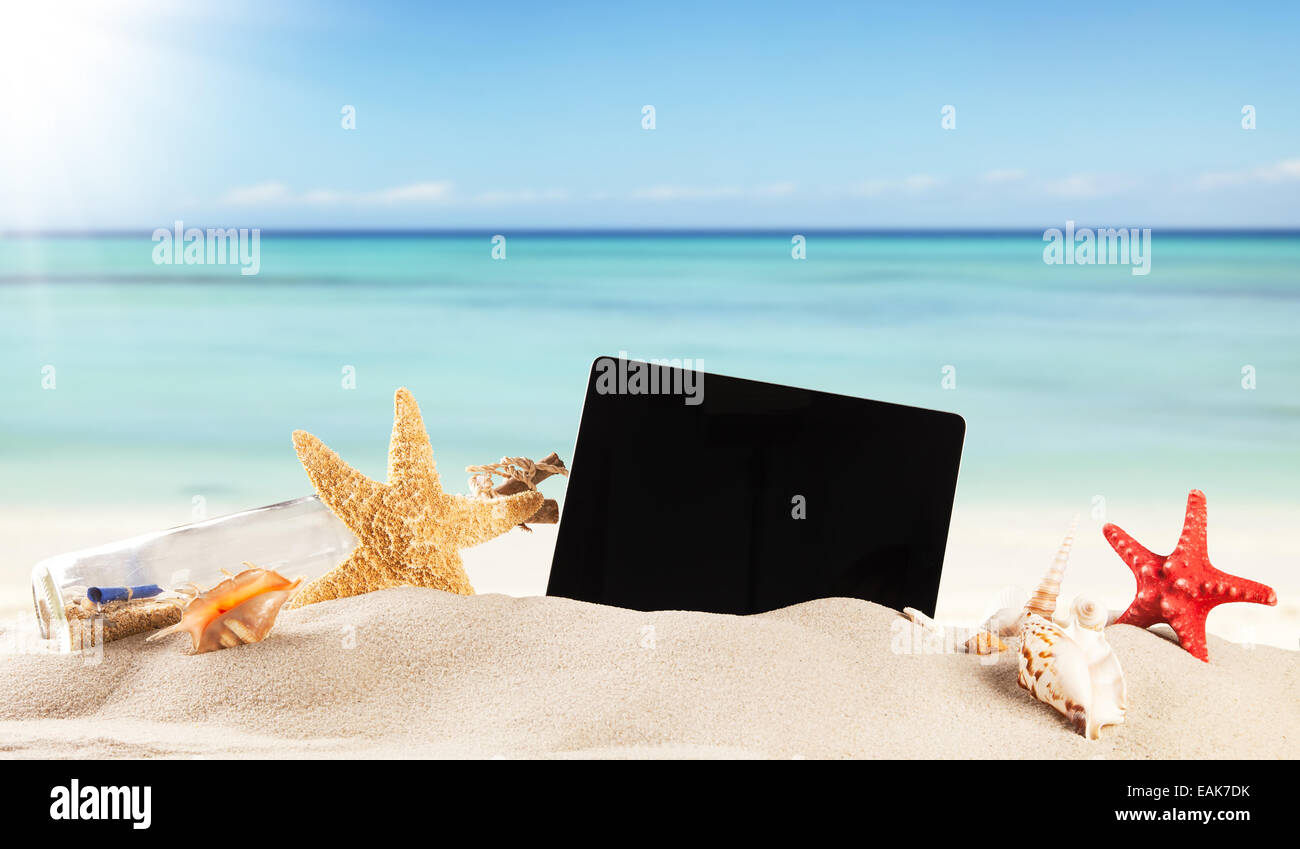 Concepto de verano con playa, tabletas y accesorios, desenfoque de fondo de mar Foto de stock