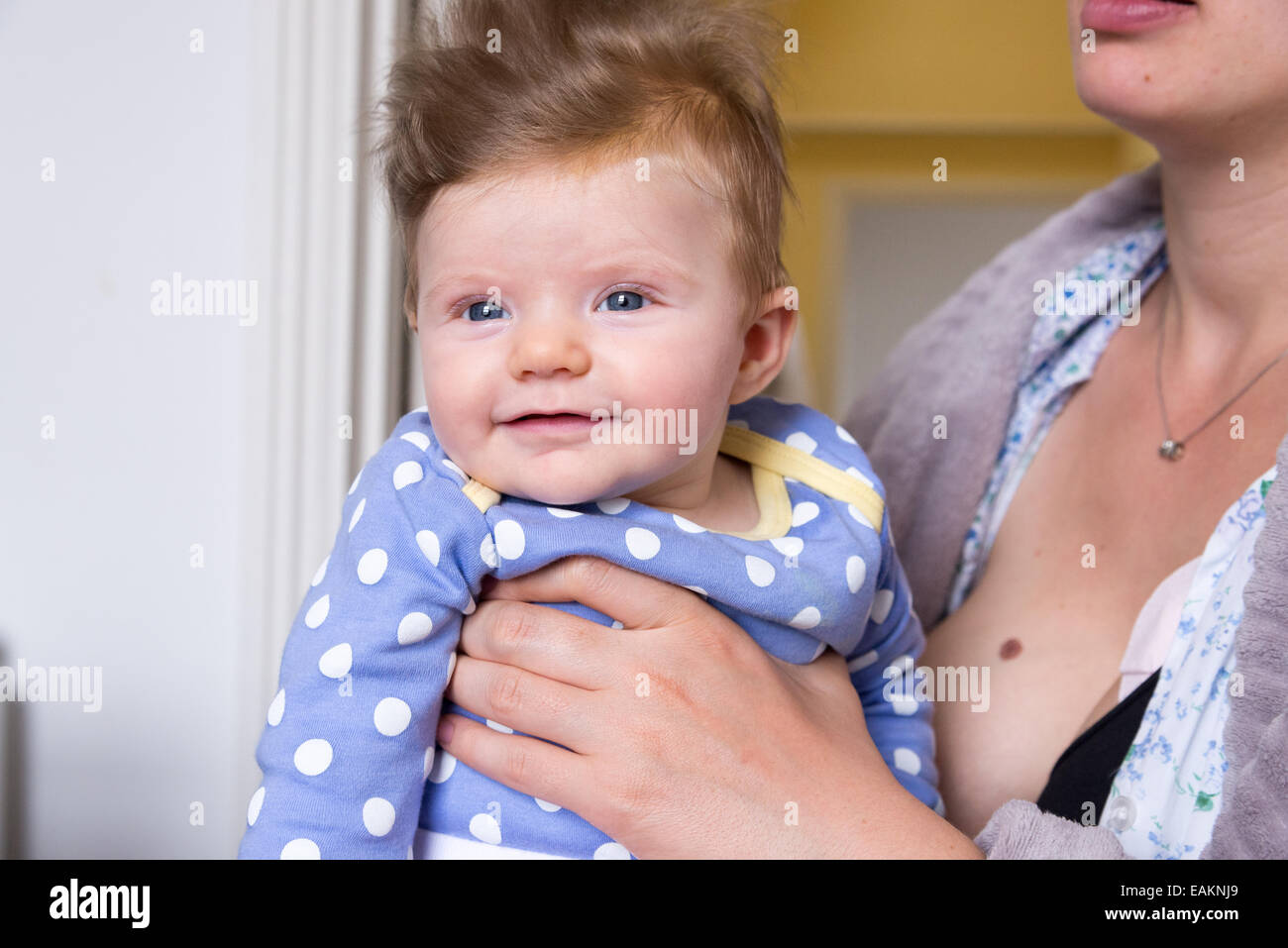La madre la celebración de tres meses de edad chica con mucho pelo Foto de stock