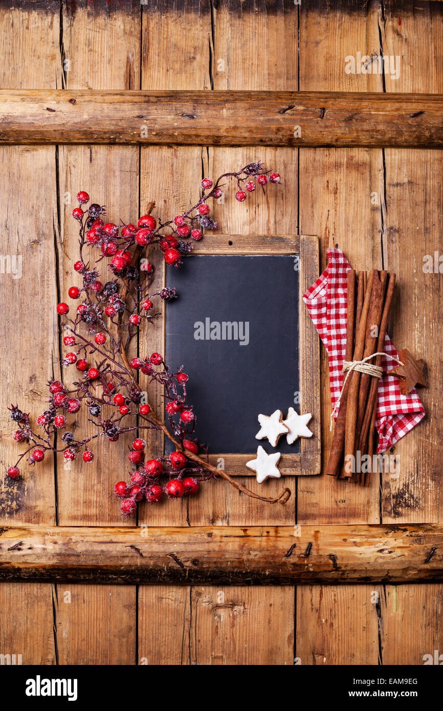 Vintage Christmas background con pizarra, rama con bayas rojas, Xmas cookies y palitos de canela Foto de stock