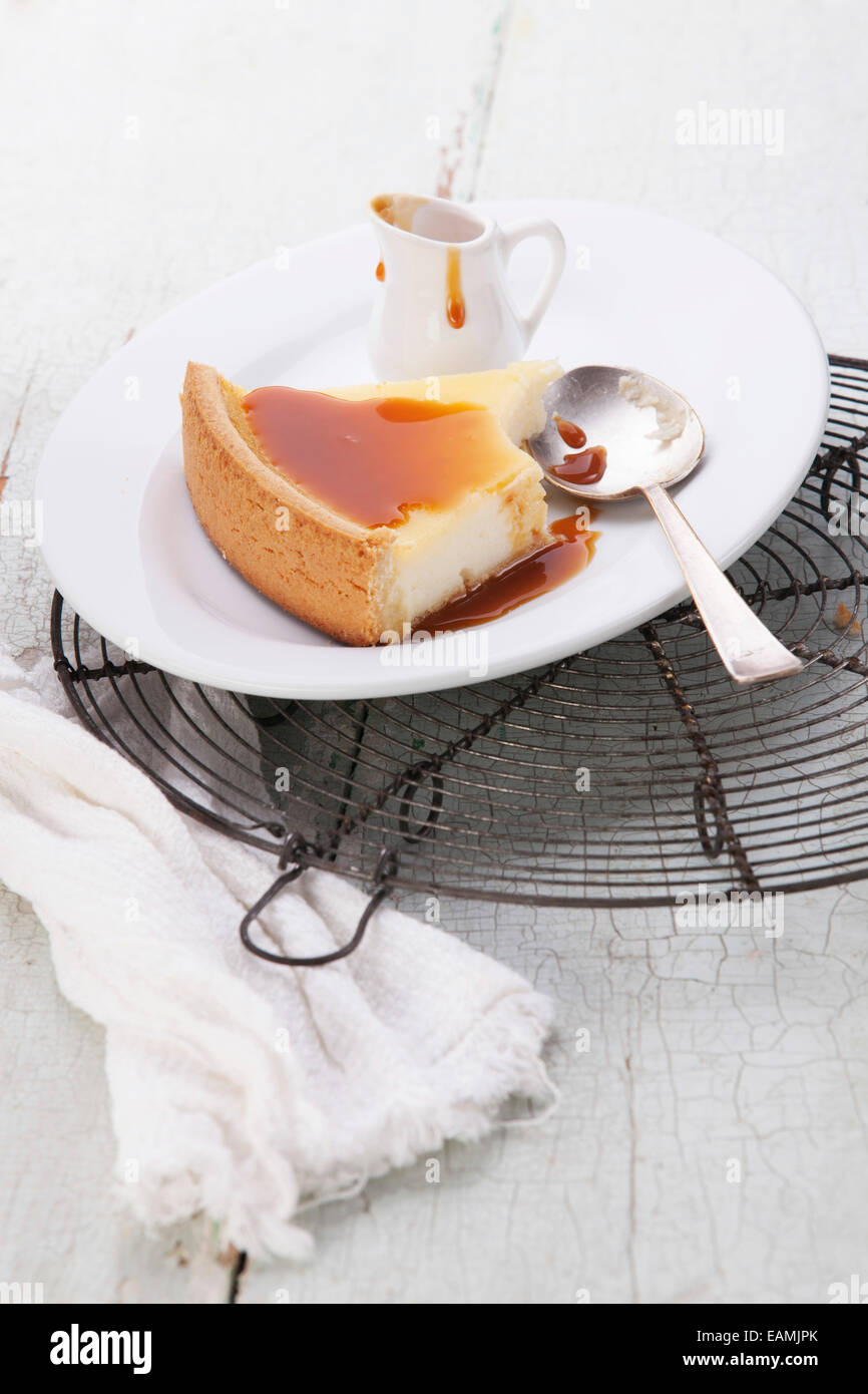 Cheesecake clásico y salsa de caramelo en la placa en la textura del fondo azul Foto de stock