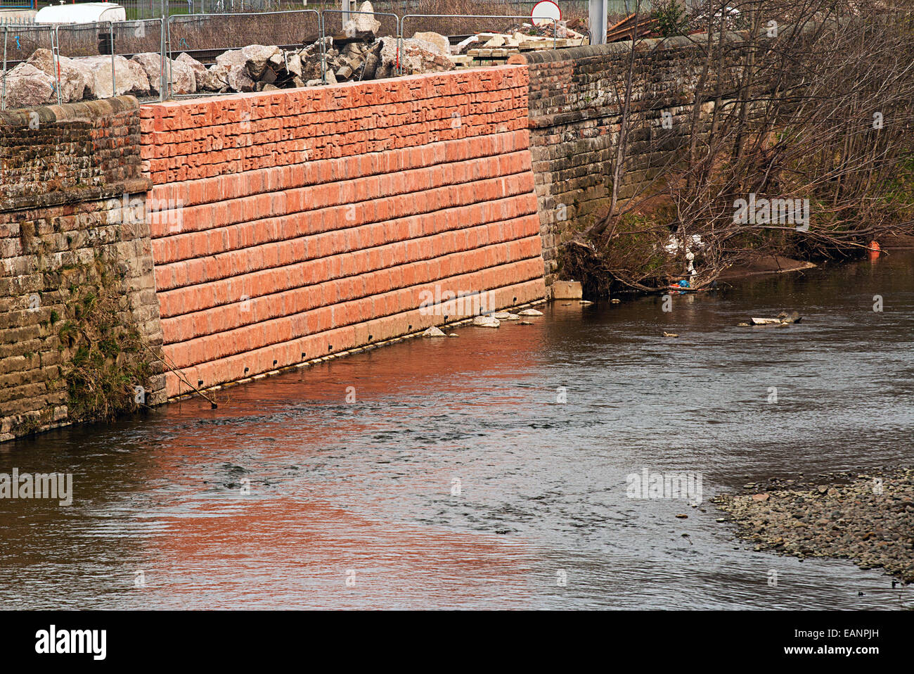 Dañado muro de inundación que ha sido reparado debido a una reciente violación rompió las orillas del río durante una tormenta. Foto de stock