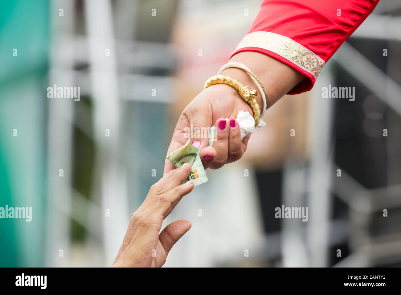 Mujer rica con pulsera de oro dando dinero a un hombre. Foto de stock