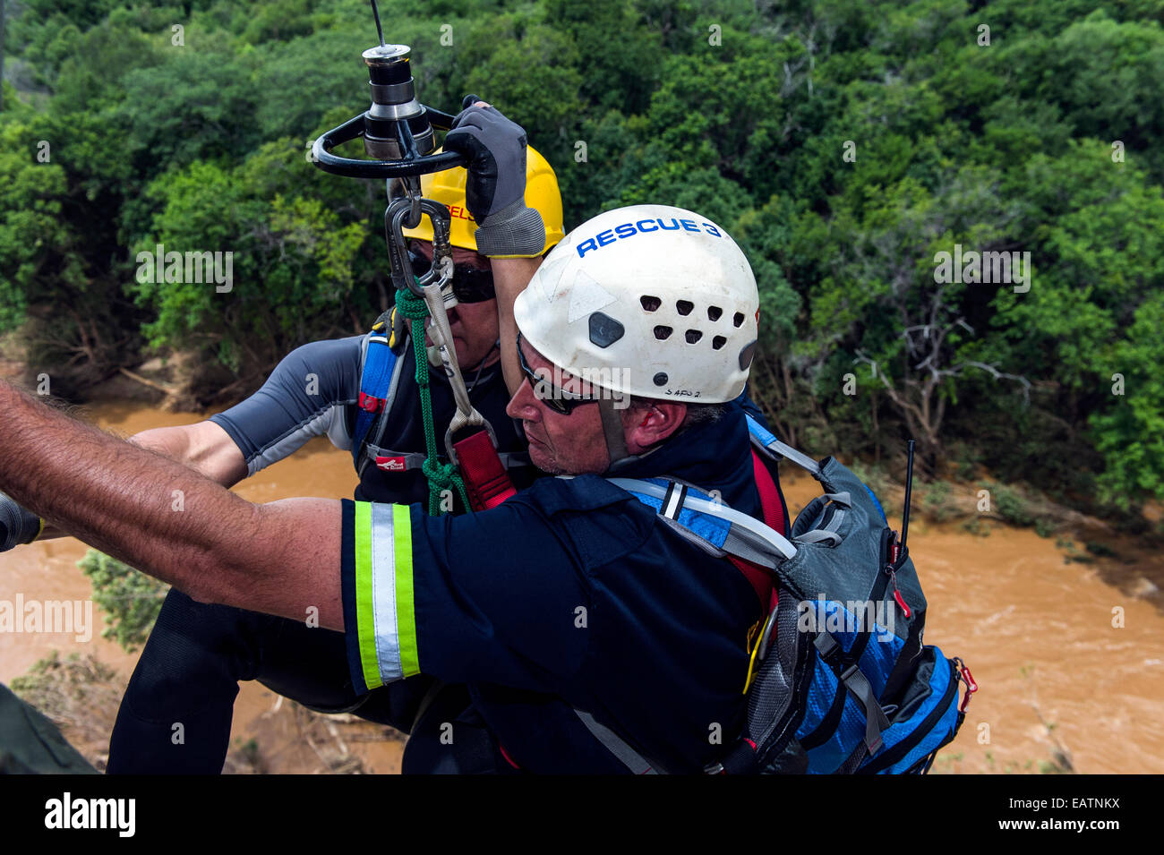 Fuerza Aérea y la policía de equipo de rescate descenderá en un cabrestante para un río inundado. Foto de stock